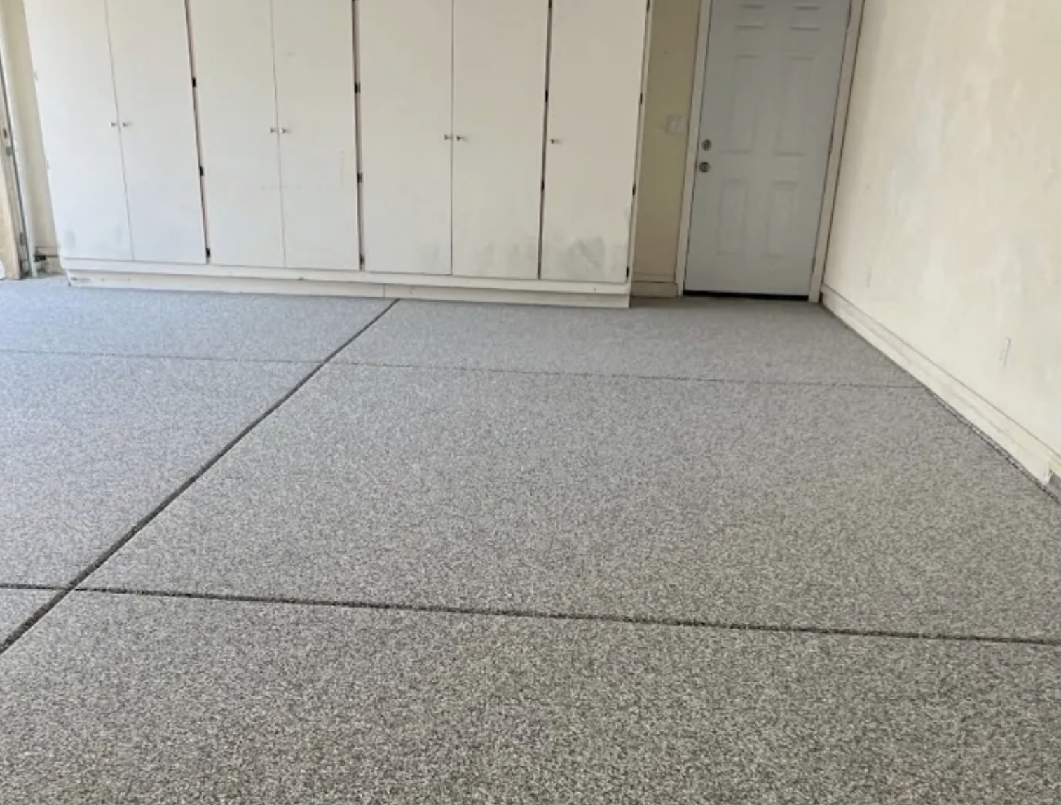Clean residential garage with light gray flake coating and storage cabinets