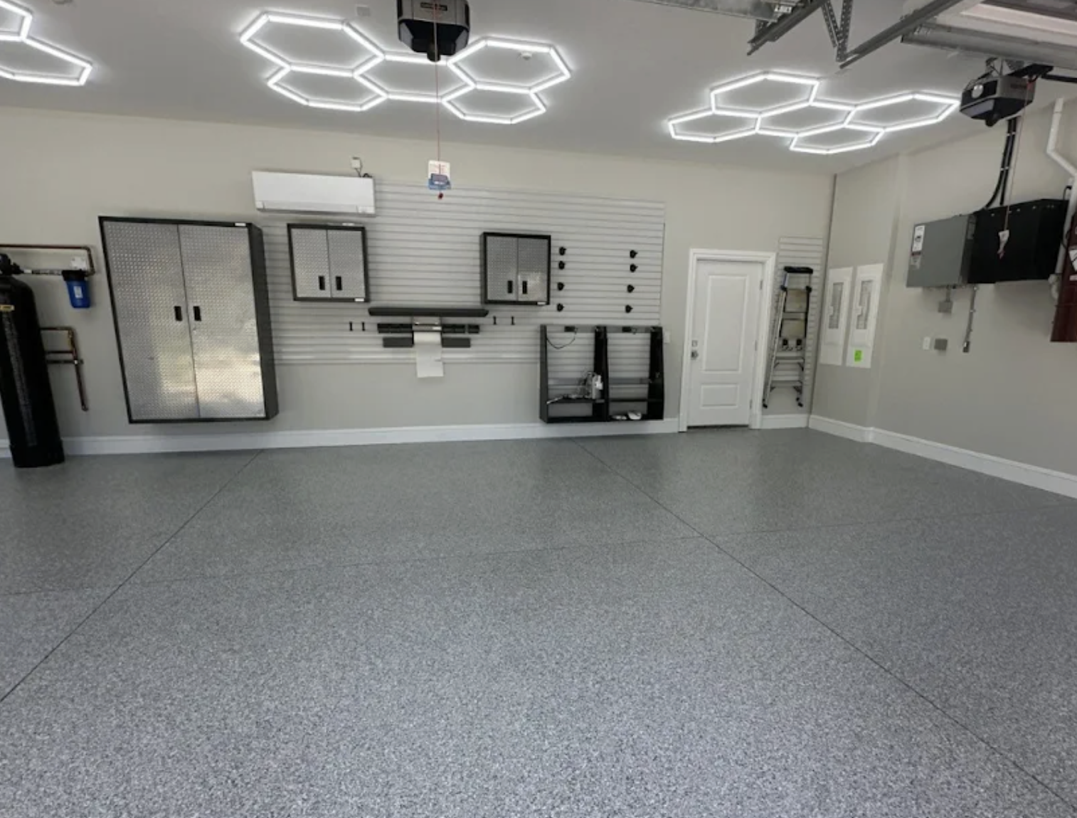 Finished gray polyaspartic garage floor with modern storage and bright ceiling lighting