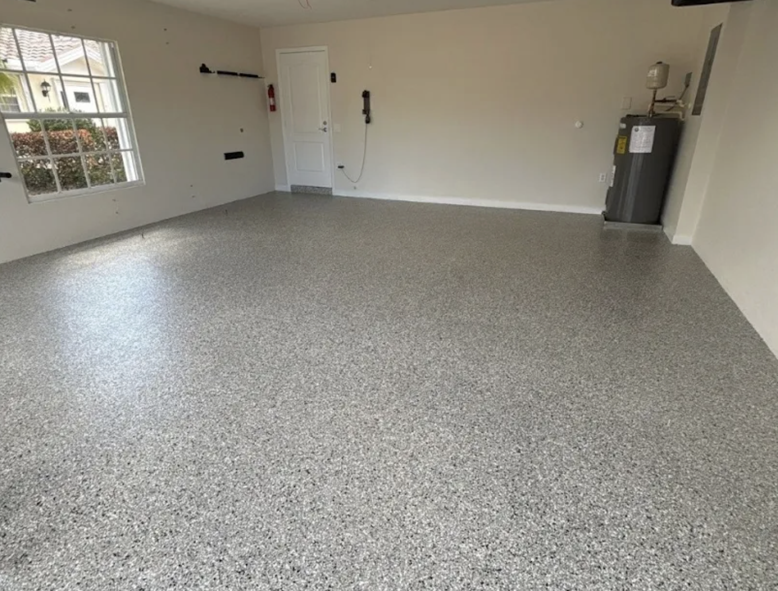 Freshly coated garage floor with a bright window and uniform decorative flake finish
